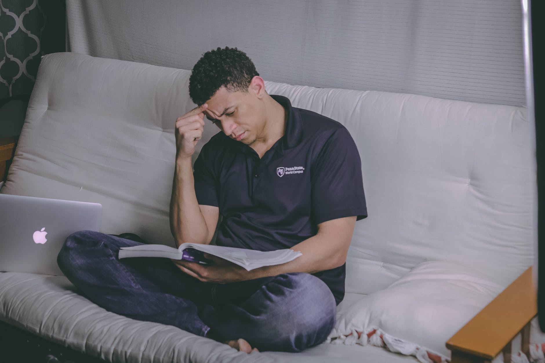 man sitting on sofa reading book